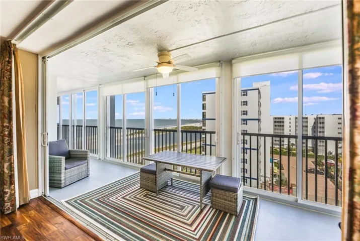 Sunroom with a water view, expansive windows, and wood finished floors