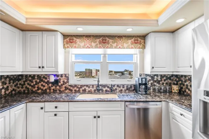 Kitchen featuring white cabinets, stainless steel appliances, dark stone countertops, tasteful backsplash, and recessed lighting