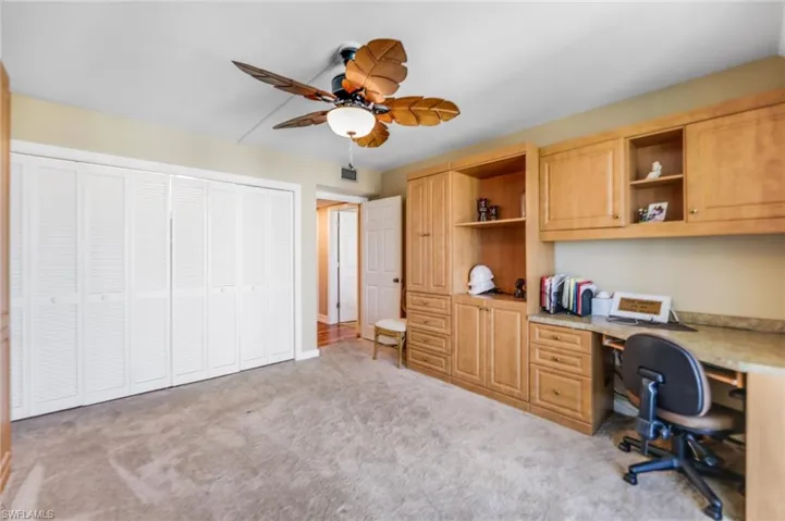 Office with a ceiling fan, built in study area, and light colored carpet