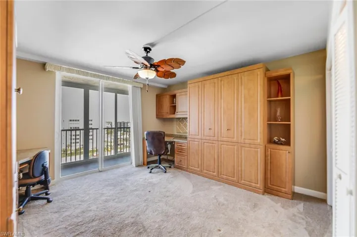 Office space featuring built in desk, light carpet, and a ceiling fan