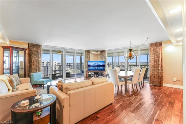 Living room with wood finished floors, floor to ceiling windows, and a chandelier