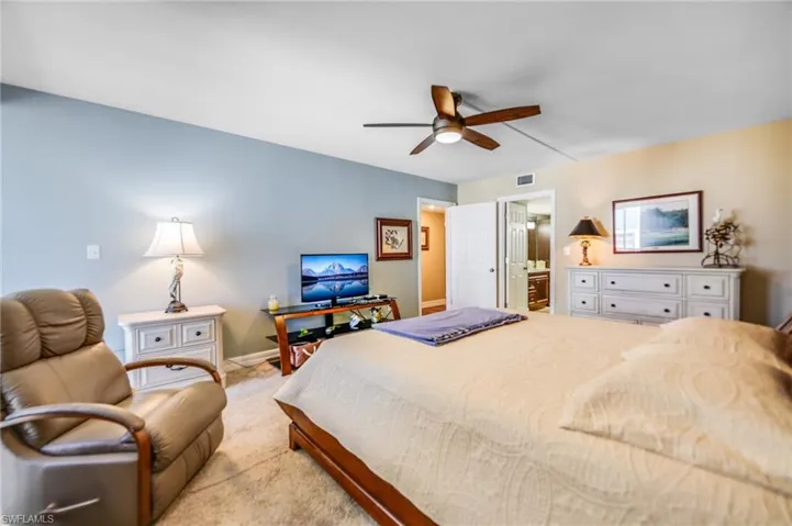 Carpeted bedroom featuring ensuite bathroom and ceiling fan