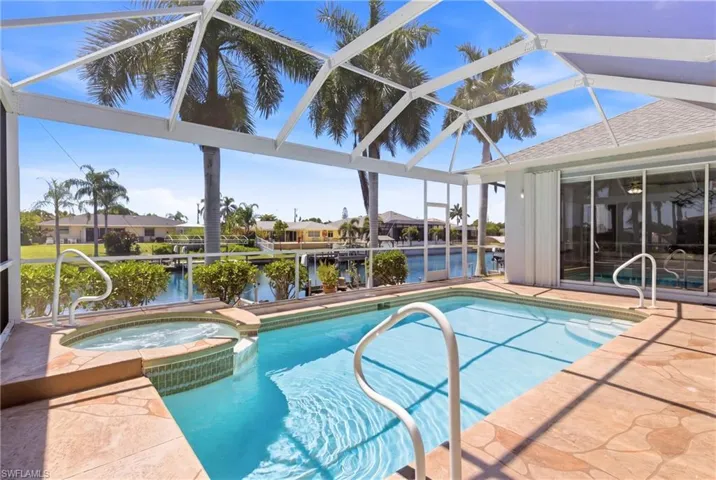 The property features a screened-in pool and an integrated hot tub, with a paved surround