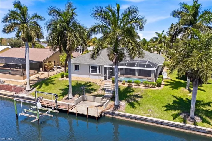 The property features a screened-in pool area, a well-maintained lawn, and mature palm trees