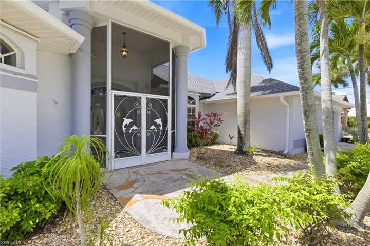 The property features a screened entry with decorative double doors, complemented by architectural columns and an overhead light fixture