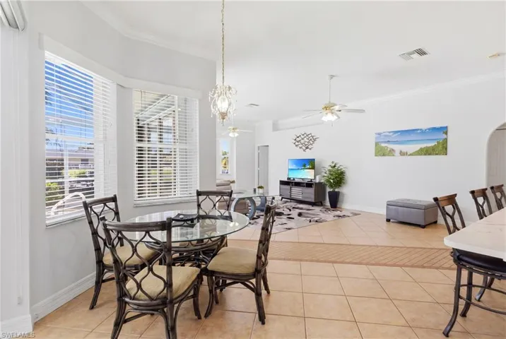Open concept living area with tiled flooring, bay windows, and a ceiling fan