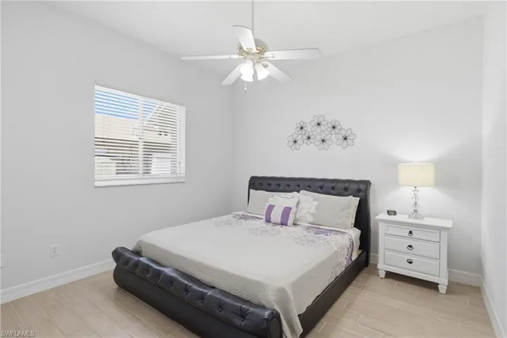 This room features light-colored flooring, a window with horizontal blinds, and a ceiling fan with integrated lighting