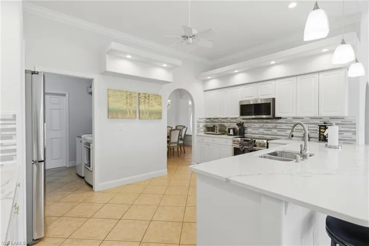 Kitchen featuring white cabinetry, stainless steel appliances, a white quartz countertop, and pendant lighting