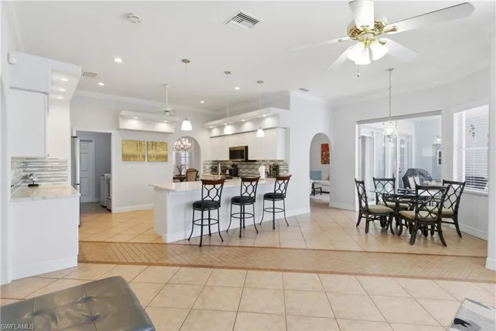The property features a kitchen with white cabinetry, a kitchen island, and a dining area with a chandelier