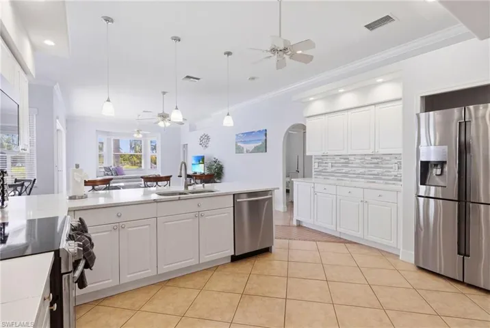 The kitchen features white cabinetry, white countertops, tile flooring, and stainless steel appliances including a refrigerator and dishwasher