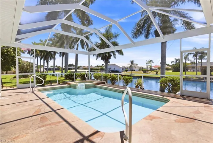 The property features a screened-in pool area with a spa, offering views of a canal and distant properties