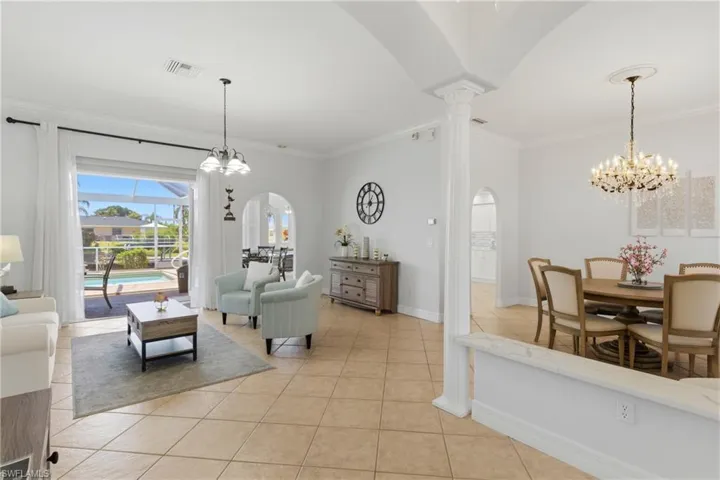 This property features an open-concept living area with tiled flooring, leading to a screened-in patio and pool area