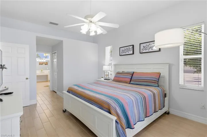 Spacious room featuring light-colored flooring, a ceiling fan with integrated lighting, and windows providing natural light