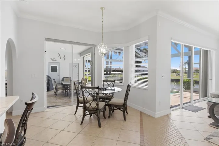Dining space featuring tiled flooring, a bay window with blinds, and sliding glass doors leading to outdoor areas