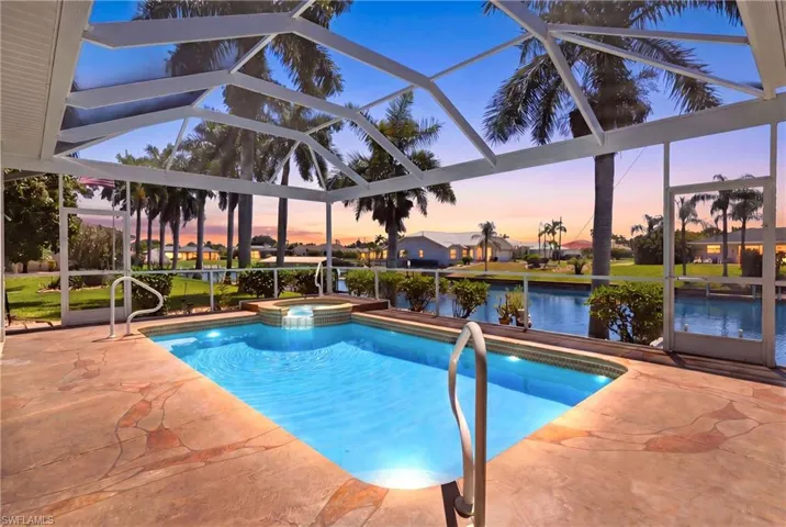 The property features a screened-in pool area with a spa, a textured patio deck, and a water view