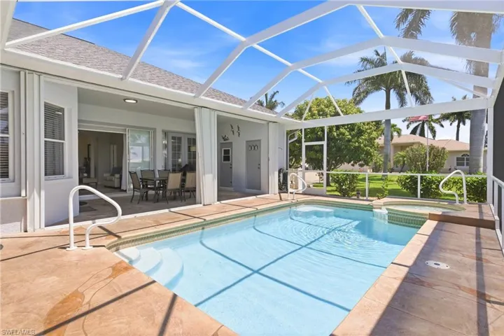 Spacious screened-in lanai featuring a swimming pool, an integrated spa, and ample patio space for outdoor living