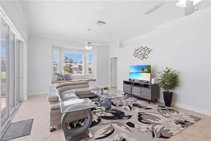 The living area features tile flooring, a bay window with an integrated window seat, and large sliding glass doors providing outdoor access