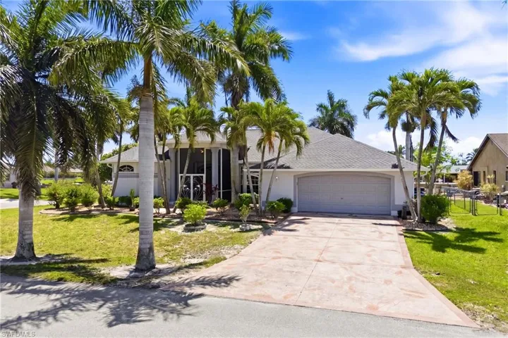 The property features a well-maintained exterior with a white facade and a gray roof, complemented by a concrete driveway and lush green lawns