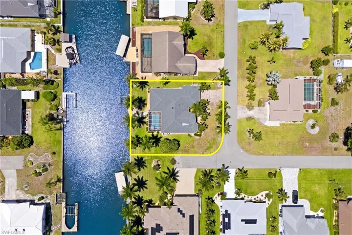 The property features a private swimming pool, a spacious yard with mature palm trees, and direct access to a canal