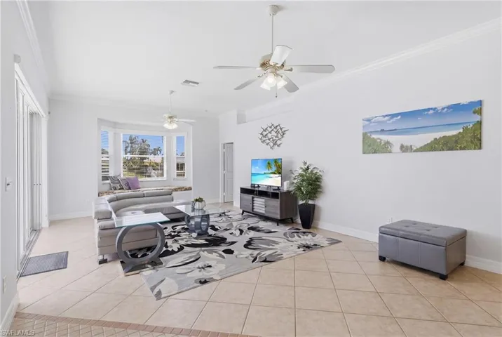 The living area features tile flooring, crown molding, and ceiling fans