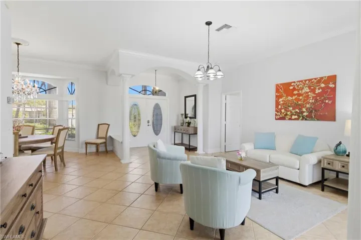 This expansive living space features tiled flooring throughout, a decorative chandelier in the dining area, and a traditional chandelier in the living area