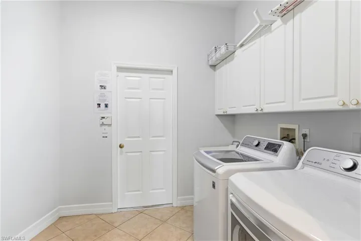 This laundry area features white cabinetry and tiled flooring