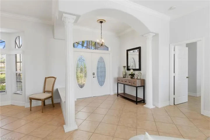 The entryway features a double-door entrance with decorative oval glass inserts, complemented by a large archway and two decorative columns