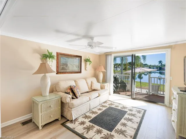 Living room with light wood-type flooring, a water view, crown molding, and a ceiling fan