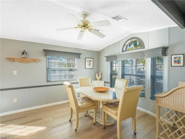 Dining space featuring lofted ceiling, light wood-type flooring, ceiling fan, and a textured ceiling