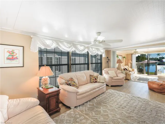 Living room with wood finished floors, crown molding, ceiling fan, and a water view