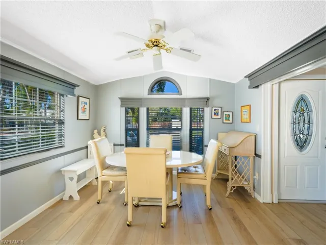 Dining space featuring lofted ceiling, light wood-style floors, ceiling fan, and a textured ceiling