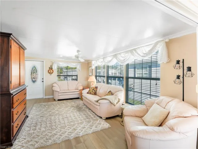 Living room with light wood-style flooring, ornamental molding, and a ceiling fan