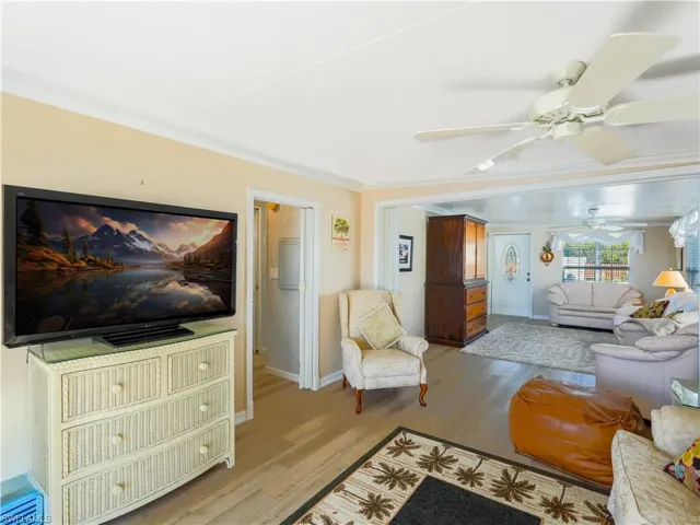 Living room featuring a ceiling fan, ornamental molding, and light wood-type flooring