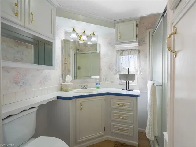 Bathroom featuring wallpapered walls, curtained shower, and vanity