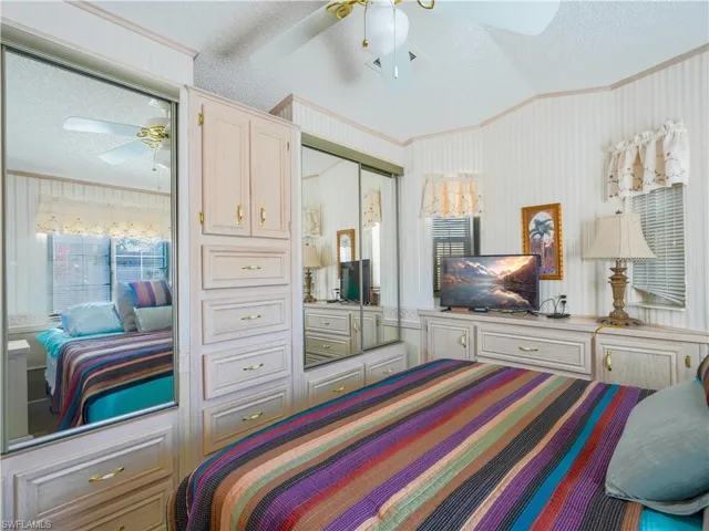 Bedroom with a textured ceiling, a ceiling fan, ornamental molding, vaulted ceiling, and a closet