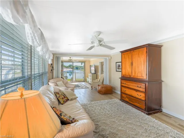 Living room featuring light wood-style flooring, crown molding, and a ceiling fan