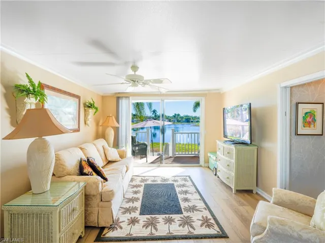 Living area with ornamental molding, wood finished floors, and ceiling fan
