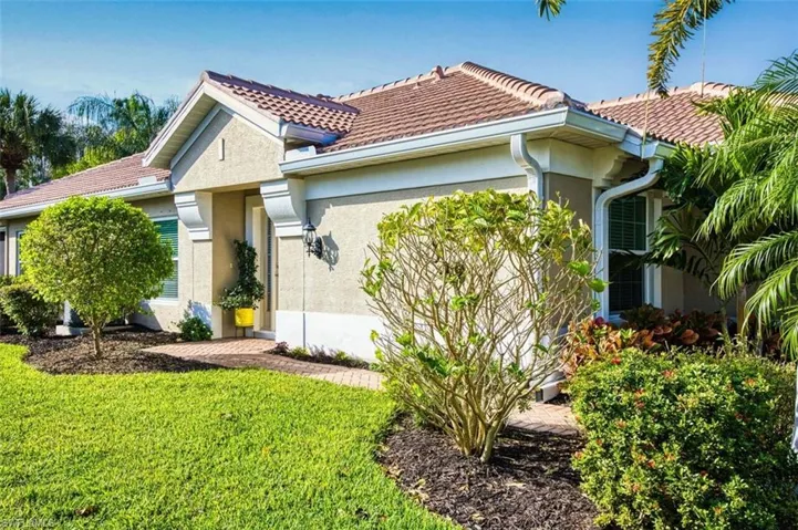 View of home's exterior with stucco siding, a yard, and a tiled roof