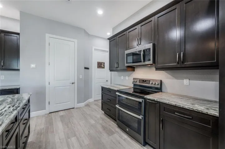 Kitchen with pantry, granite countertops, GE matte slate appliance suite.