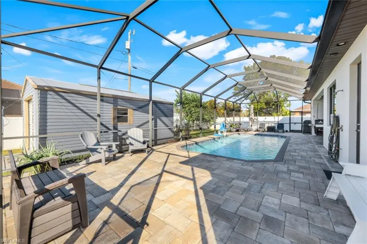 View of pool, lanai and outdoor shower on right, shed on left