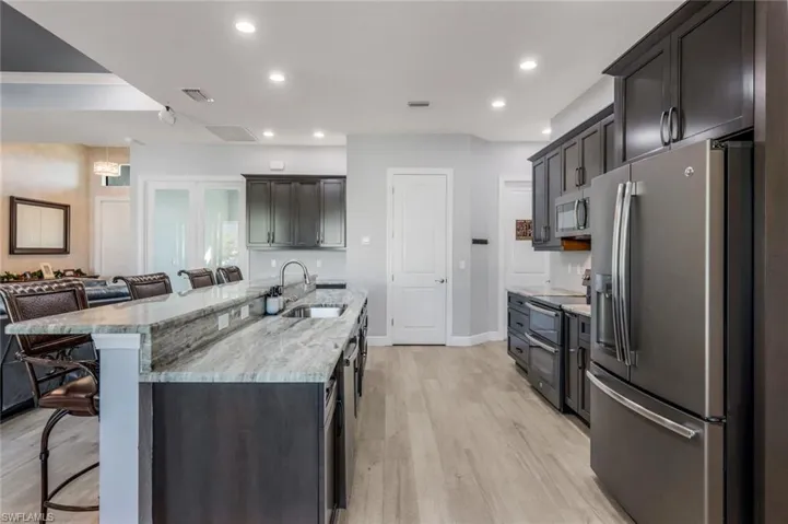 Kitchen with counter seating, granite countertops, GE matte slate appliance suite.