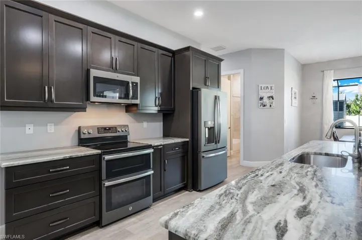 Kitchen with granite countertops, GE matte slate appliance suite.