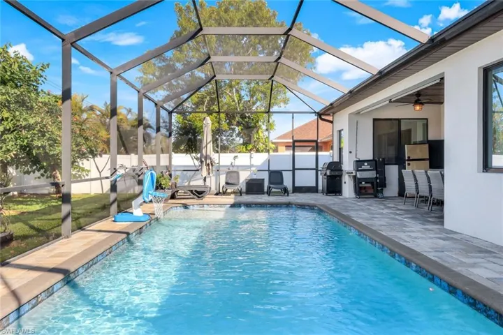 View of pool featuring a lanai, grilling area, pool water feature, and a patio