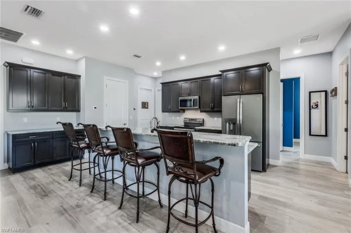 Kitchen with counter seating, granite countertops, GE matte slate appliance suite.