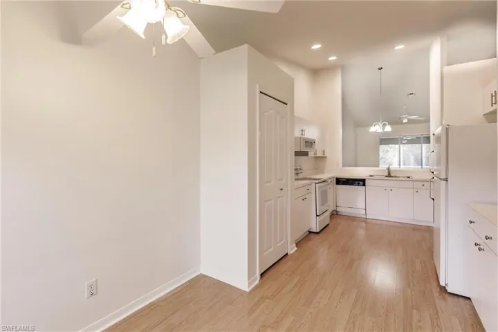 Kitchen featuring white appliances, light hardwood / wood-style floors, white cabinetry, and ceiling fan
