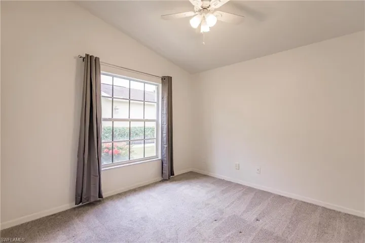 Guest room with carpet, ceiling fan, and vaulted ceiling