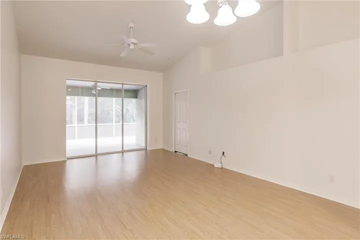 Unfurnished room featuring high vaulted ceiling, light hardwood / wood-style floors, and ceiling fan with notable chandelier