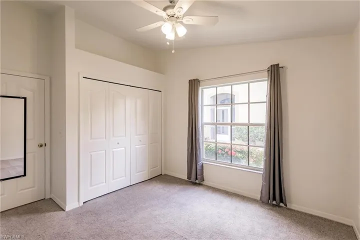 Unfurnished bedroom with a closet, ceiling fan, vaulted ceiling, and light colored carpet