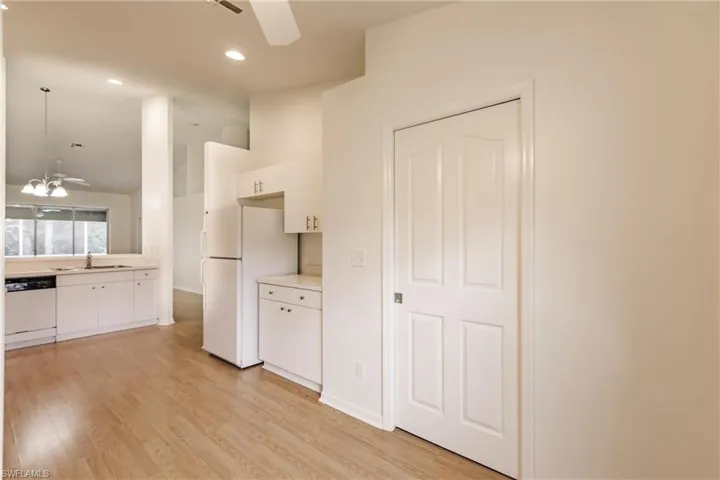 Kitchen with ceiling fan, light hardwood / wood-style floors, white cabinets, and white appliances