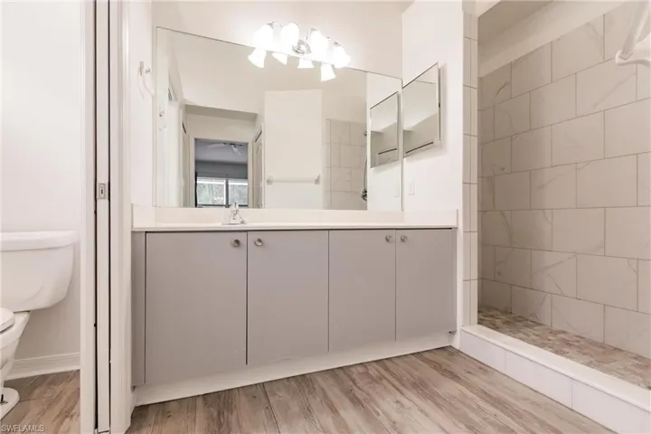 Bathroom featuring a walk-in tile shower, large vanity.